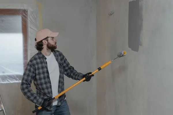 Painter rolling grey paint onto an interior wall in Sioux Falls